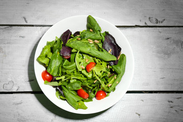 Fresh green salad in bowl on wooden table