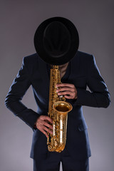 Naklejka premium Portrait of a jazz man in a suit with a hat hiding his face and
