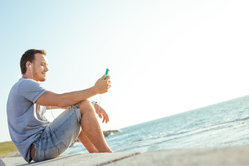 Fototapeta na wymiar handsome man sitting near the sea with mobile smartphone