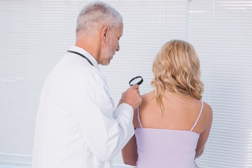 Doctor examining patient with magnifying glass