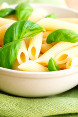 Macaroni and basil on table cloth close up