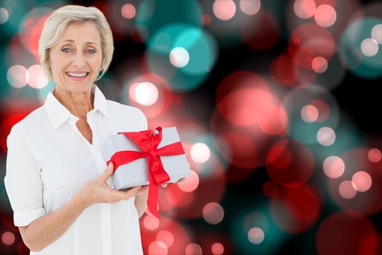 Composite image of mature woman holding gift