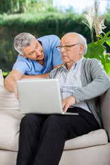 Fototapeta premium Male Nurse Assisting Senior Man In Using Laptop