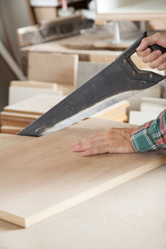 Cropped Image Of Carpenter Cutting Wood With Handsaw