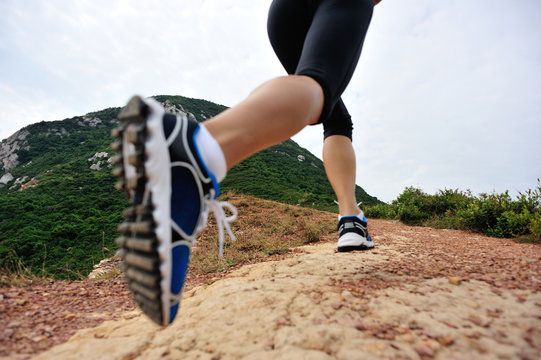 young woman legs running on seaside mountain trail 