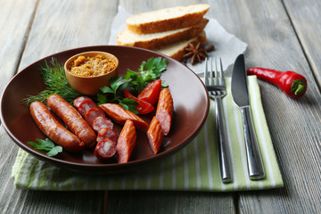 Assortment of tasty thin sausages on plate on wooden background