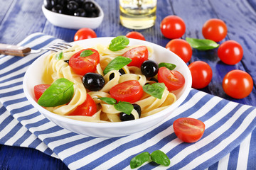 Spaghetti with tomatoes, olives and basil leaves