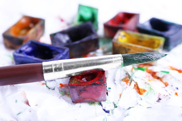 Obraz premium Watercolor paint cubes with brush and spilled paint