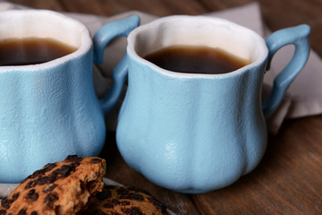 Cups of coffee with cookies and napkin on wooden table