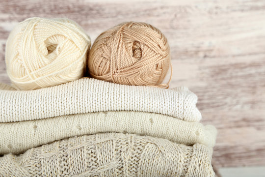 Knitting clothes and yarn on wooden background