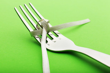Stages of tying bow on fork on green background, close-up