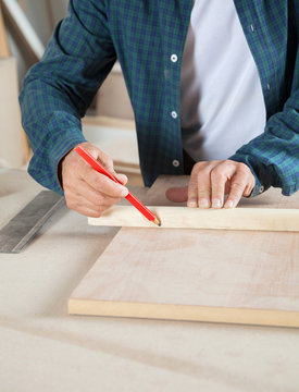Carpenter Marking On Wood With Pencil