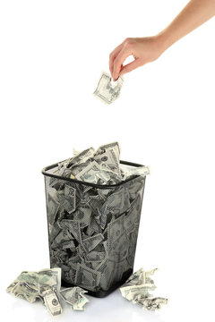 Hand throwing money into trash can isolated on white