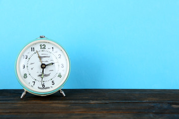 Old alarm clock on wooden table on blue background