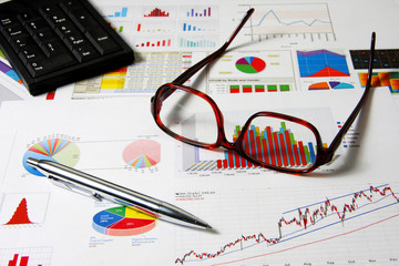Glasses, numpad and pen on finance chart