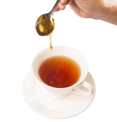 Female hand mixing honey with tea over white background