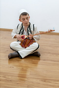 Sitzender Junge spielt Saiteninstrument