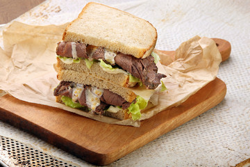 Sandwich with roast beef, lettuce and truffle sauce on a choppin