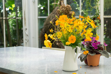 Decorative yellow flowers in the white jug on the table