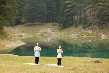 Zwei Frauen beim Yogatraining vor einem See