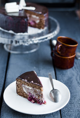 piece of chocolate cake with cream and cherry on white plate