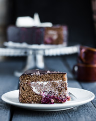 piece of chocolate cake with cream and cherry on white plate
