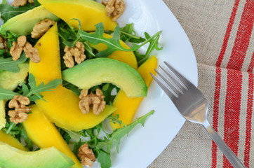 Fruit salad with mango, avocado, rucola and walnuts