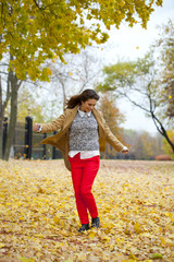 Young woman in fashion coat walking in autumn park