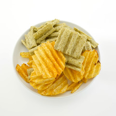 Mixed potato crisps and corn flake cereal on white background