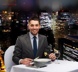 smiling man with tablet pc eating main course