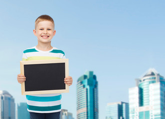 Obraz premium smiling little boy holding blank black chalkboard