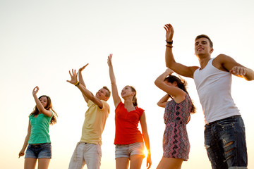 Obraz premium smiling friends dancing on summer beach