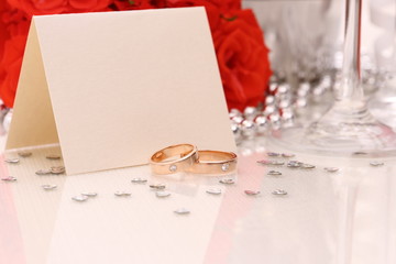 Two golden wedding rings with card, red roses