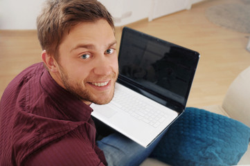 portrait of attractive young man with laptop on the sofa at home - Powered by Adobe