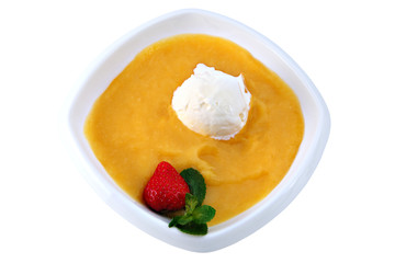 ball of ice cream floats in mango puree, on white.