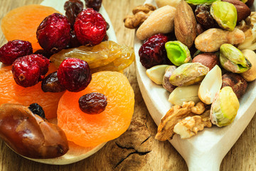 Varieties of dried fruits and nuts on wooden spoons.