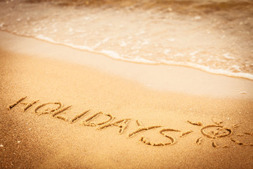 The word holidays written in the sand on a beach