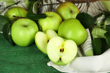 Ripe apples in metal basket with napkin on wooden background