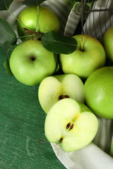 Ripe apples in metal basket with napkin on wooden background