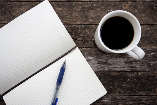 image of coffee cup with notebook and pen on an old wooden table