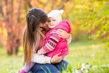 beautiful mother embracing kid girl outdoors in fall