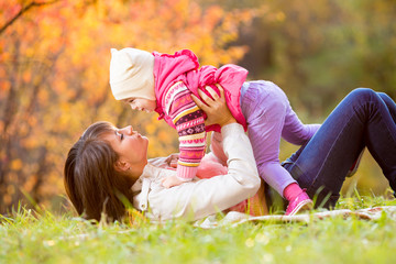 happy woman and daughter child play outdoors in fall