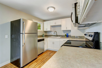 Furnished kitchen room with white cabinets and steel appliances