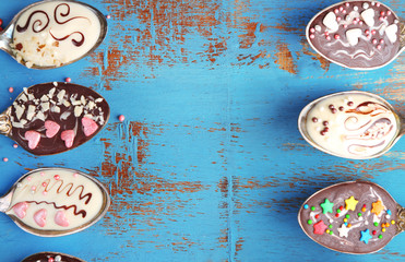 Spoons with tasty chocolate for party on old blue wooden table