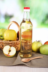 Apple cider vinegar in glass bottle and ripe fresh apples,