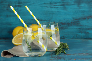 Tasty cool beverage with lemon and thyme, on wooden background