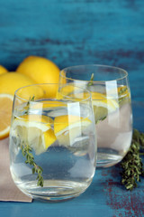 Tasty cool beverage with lemon and thyme, on wooden background