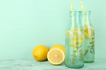 Tasty cool beverage with lemon and thyme, on wooden background
