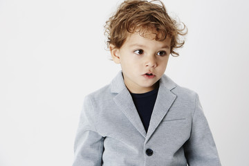 Smart young boy in suit jacket, looking away