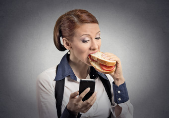 woman reading message on smartphone eating sandwich